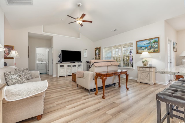 living room with washer / clothes dryer, high vaulted ceiling, ceiling fan, and light hardwood / wood-style flooring