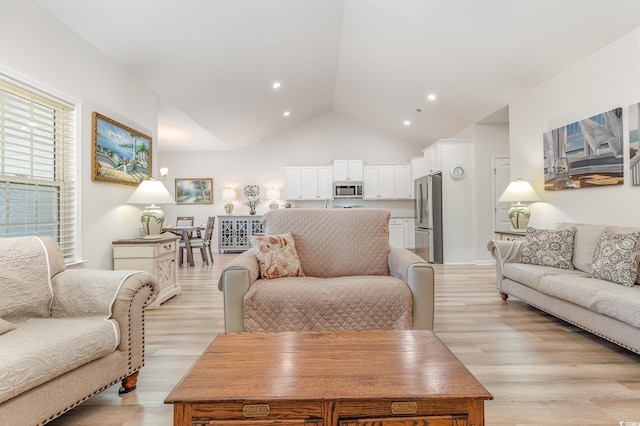 living room featuring lofted ceiling and light hardwood / wood-style floors