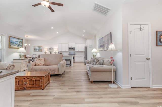 living room with lofted ceiling, ceiling fan with notable chandelier, and light wood-type flooring