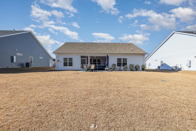 rear view of house with cooling unit and a lawn