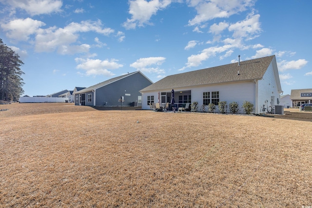 rear view of house with a yard and central AC