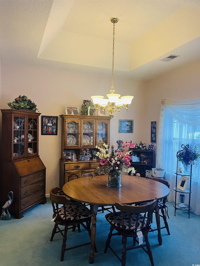 dining room with a tray ceiling, light carpet, and a notable chandelier