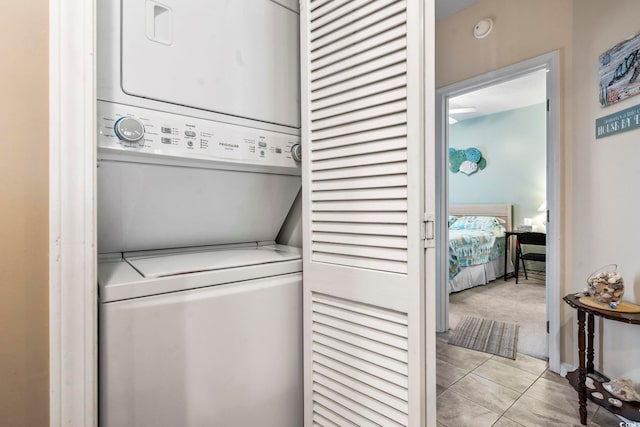 laundry area featuring stacked washer / dryer and light carpet