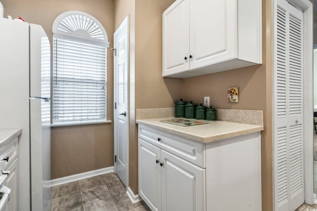 kitchen featuring white cabinetry, light tile patterned flooring, and white refrigerator