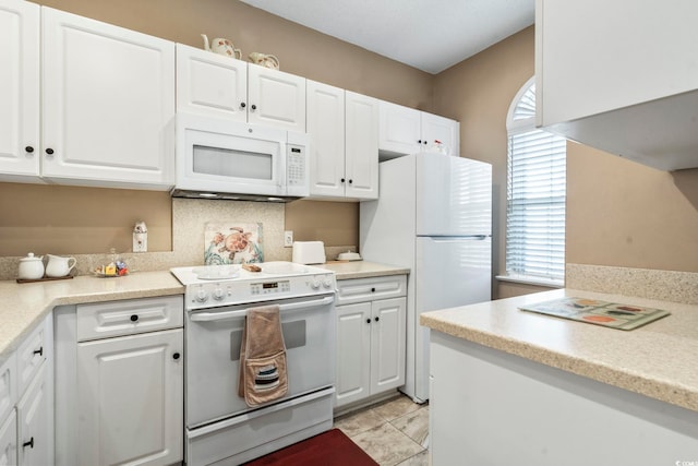 kitchen with backsplash, white appliances, and white cabinets