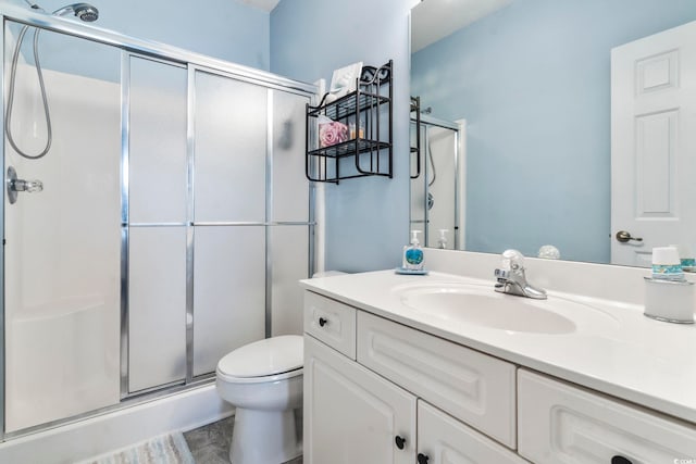 bathroom featuring vanity, a shower with shower door, and toilet