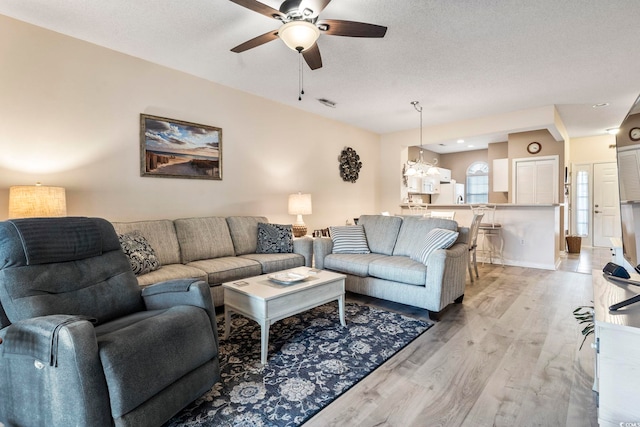 living room featuring ceiling fan, a textured ceiling, and light wood-type flooring