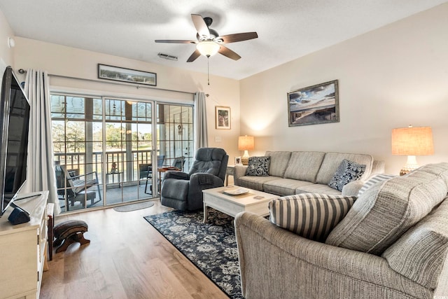 living room with ceiling fan, wood-type flooring, and a textured ceiling