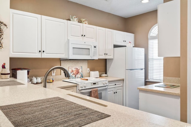 kitchen featuring white cabinets and white appliances