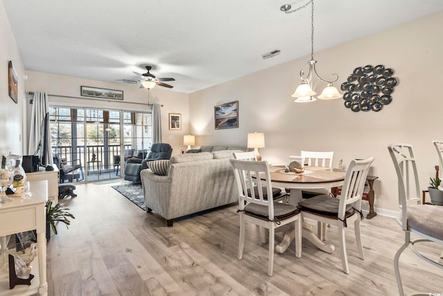 dining space with ceiling fan with notable chandelier and light hardwood / wood-style floors