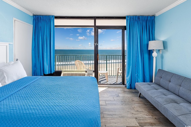 bedroom with a water view, wood-type flooring, crown molding, and access to exterior