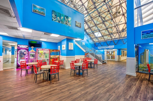 game room with a high ceiling, wood-type flooring, and a paneled ceiling