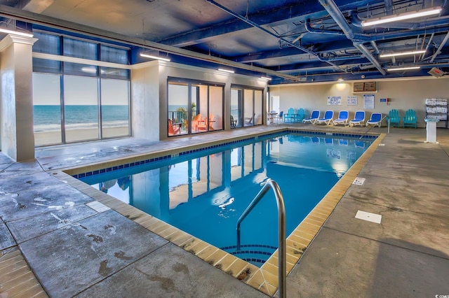 view of swimming pool with a beach view and a water view