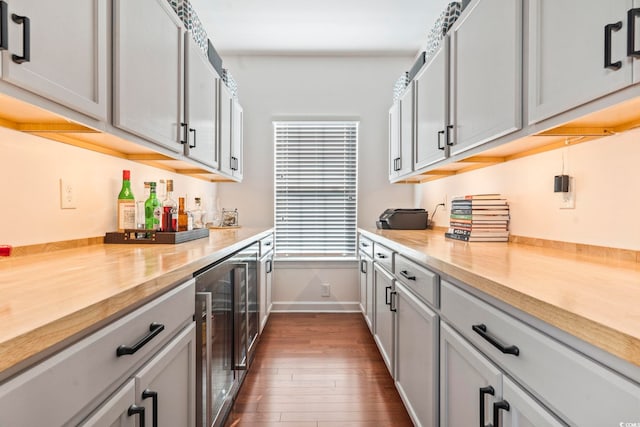 kitchen featuring dark hardwood / wood-style flooring, gray cabinets, beverage cooler, and butcher block counters