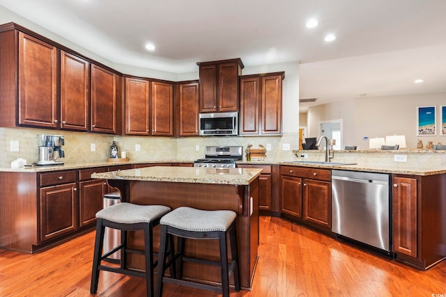 kitchen featuring sink, a breakfast bar area, hardwood / wood-style floors, stainless steel appliances, and a kitchen island