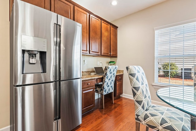 kitchen featuring dark wood-type flooring, built in desk, light stone countertops, and stainless steel refrigerator with ice dispenser