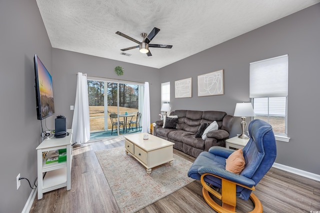 living room with ceiling fan, wood-type flooring, and a textured ceiling