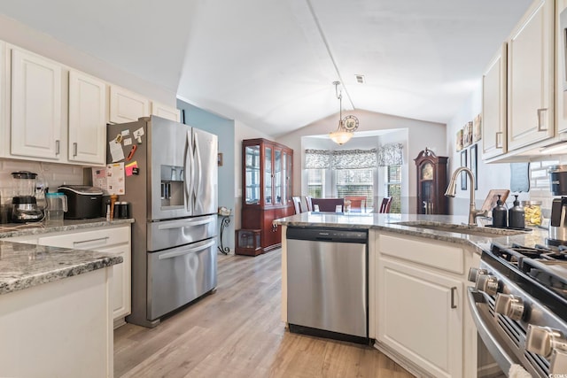 kitchen featuring white cabinetry, stainless steel appliances, vaulted ceiling, and light stone counters