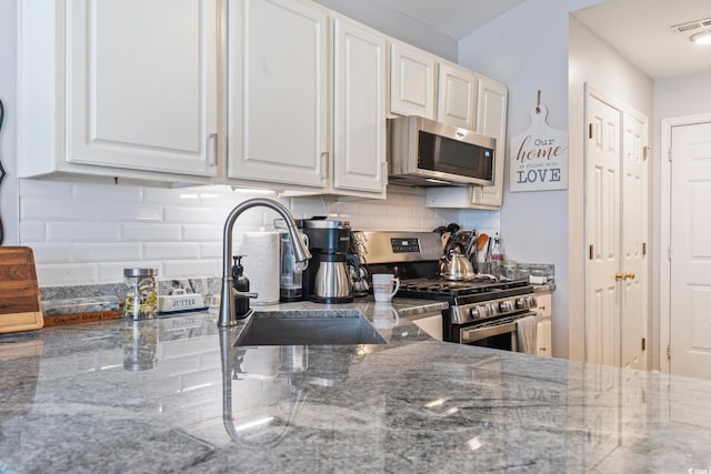 kitchen with white cabinetry, appliances with stainless steel finishes, and stone counters