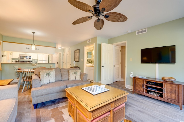living room with ceiling fan and light wood finished floors