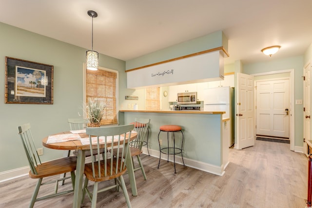 dining room with light wood-type flooring and baseboards