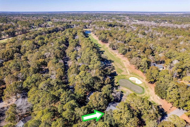aerial overview of property's location with a golf course and a heavily wooded area