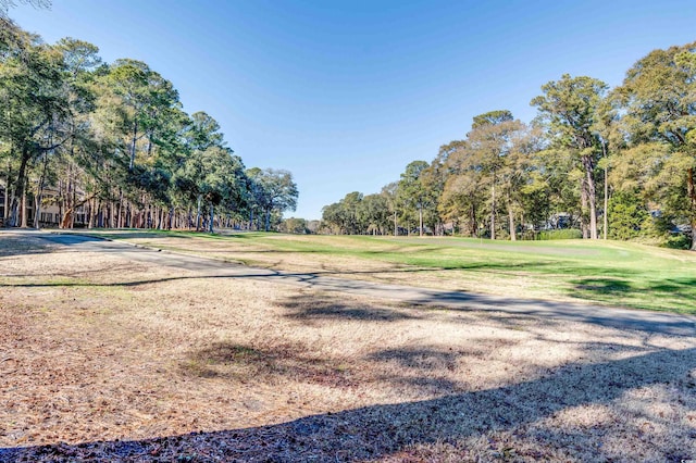view of home's community featuring a lawn, view of wooded area, and golf course view