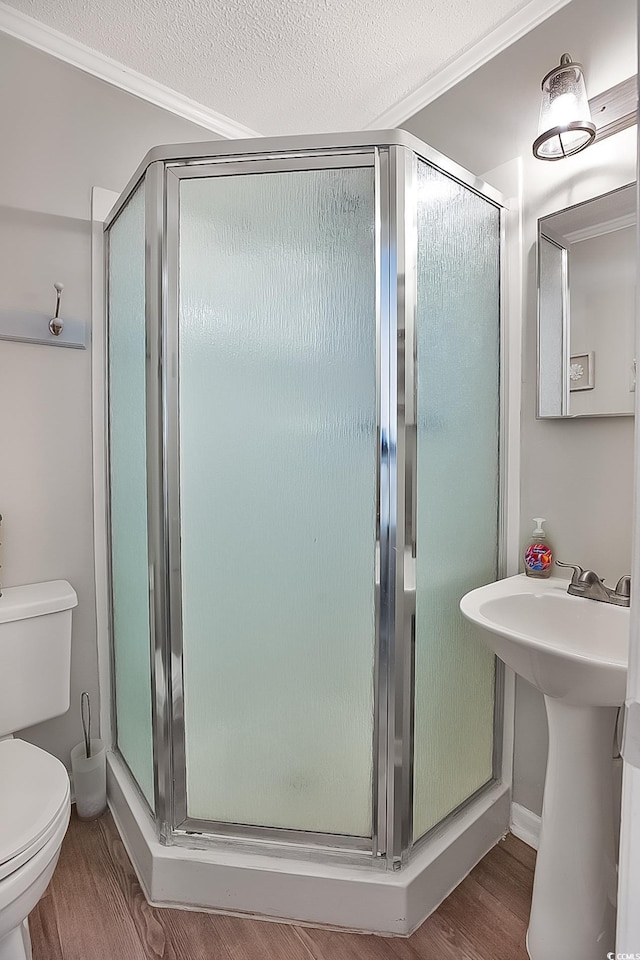 bathroom featuring a shower with shower door, sink, hardwood / wood-style flooring, toilet, and a textured ceiling