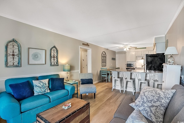 living room featuring ornamental molding, ceiling fan, and light hardwood / wood-style floors