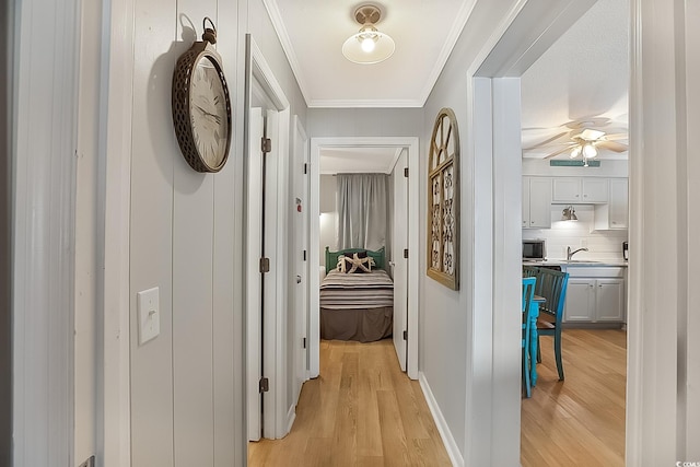 corridor featuring ornamental molding, sink, and light wood-type flooring