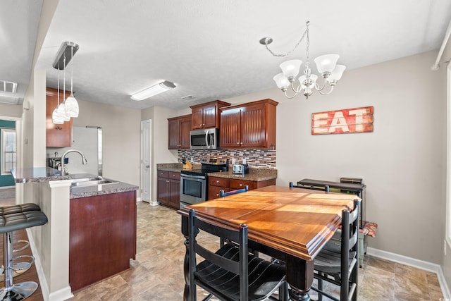 kitchen with a breakfast bar, a peninsula, a sink, stainless steel appliances, and backsplash