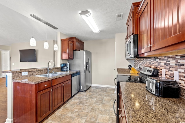 kitchen featuring visible vents, a peninsula, a sink, stainless steel appliances, and backsplash