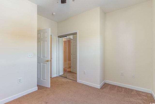 unfurnished bedroom featuring light carpet, lofted ceiling, and a closet