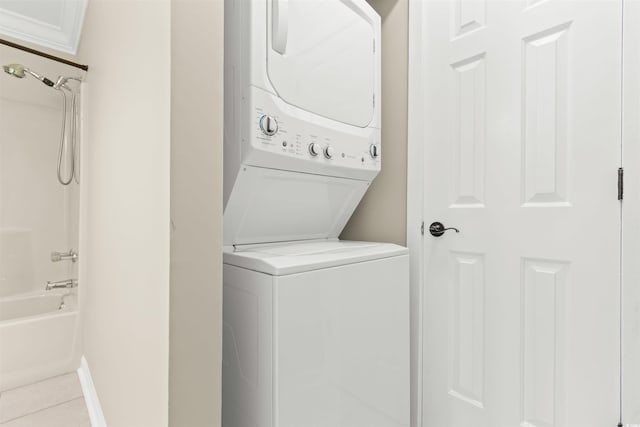 washroom with stacked washer / drying machine and light tile patterned floors