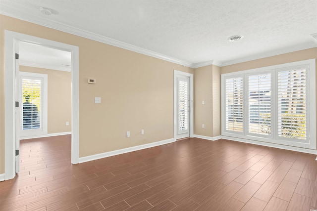 empty room featuring dark hardwood / wood-style flooring, ornamental molding, and a textured ceiling