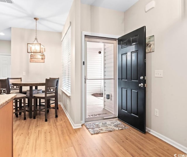 entryway with a notable chandelier, baseboards, visible vents, and light wood finished floors