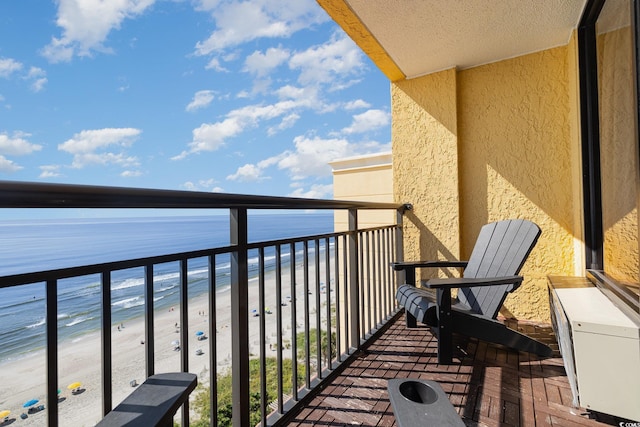 balcony with a water view and a view of the beach