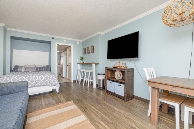 bedroom featuring wood-type flooring, ornamental molding, and a textured ceiling