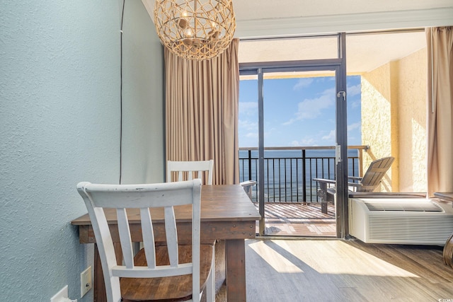 dining area with hardwood / wood-style flooring, a wall mounted AC, a chandelier, and a water view