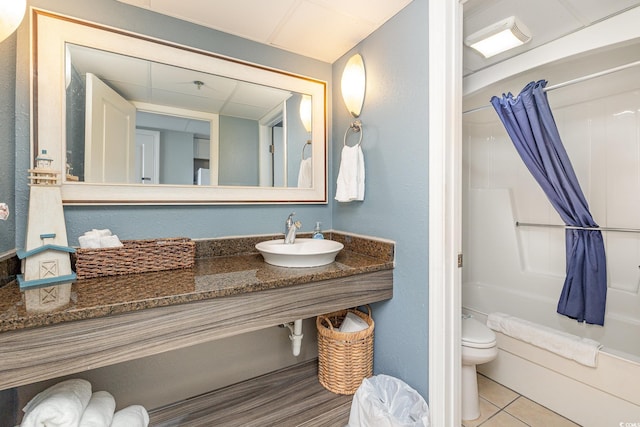 full bathroom featuring a paneled ceiling, sink, tile patterned flooring, toilet, and shower / bath combo with shower curtain