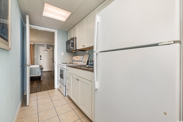 kitchen featuring light tile patterned floors, white appliances, a paneled ceiling, and white cabinets