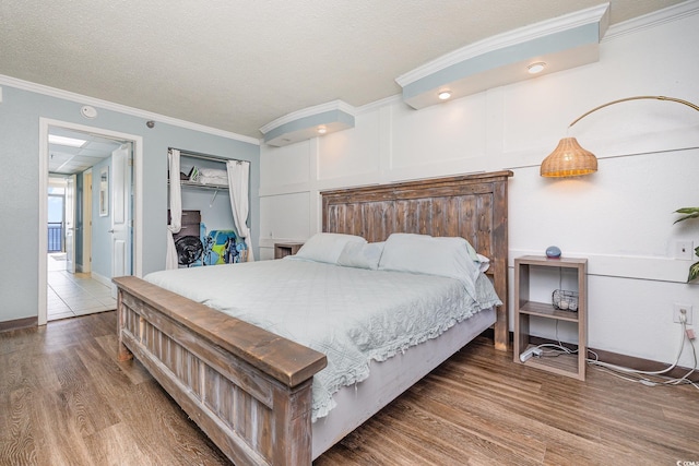 bedroom featuring crown molding, a closet, wood-type flooring, and a textured ceiling