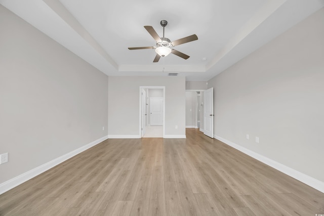 spare room featuring ceiling fan, light hardwood / wood-style floors, and a tray ceiling