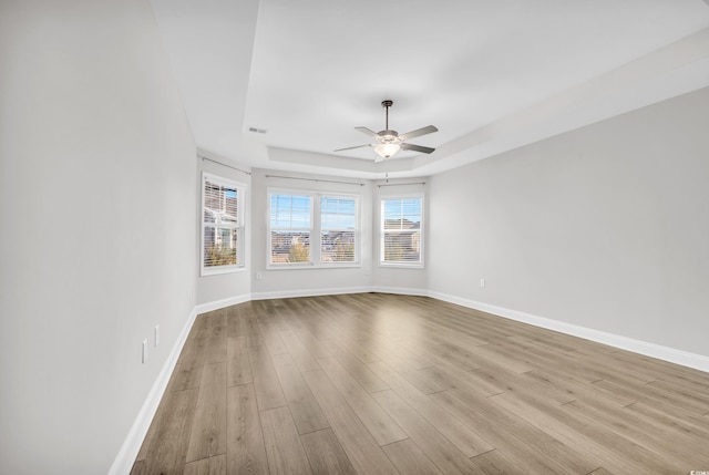 spare room featuring ceiling fan, a tray ceiling, and light hardwood / wood-style flooring