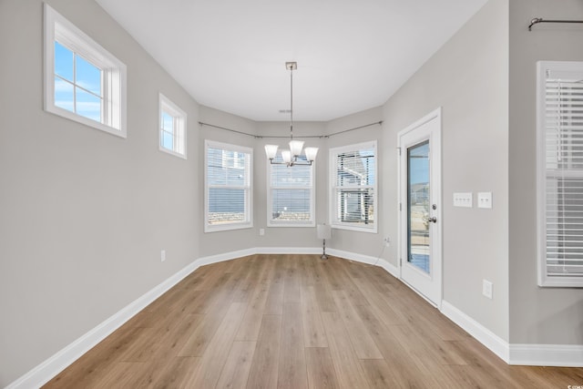 unfurnished dining area featuring a chandelier and light wood-type flooring