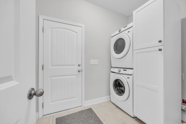 clothes washing area with cabinets and stacked washer / dryer