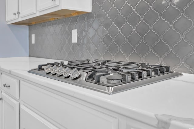 details with decorative backsplash, stainless steel gas cooktop, and white cabinets