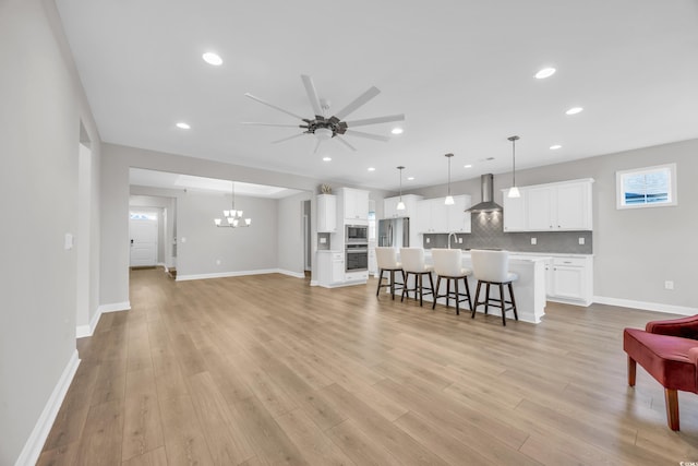 living room featuring sink, ceiling fan with notable chandelier, and light wood-type flooring