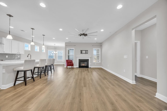 living room featuring sink, ceiling fan, and light wood-type flooring