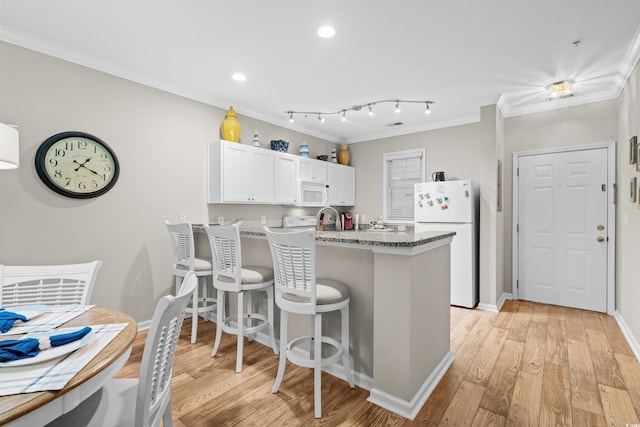 kitchen with white cabinetry, ornamental molding, light stone counters, kitchen peninsula, and white appliances